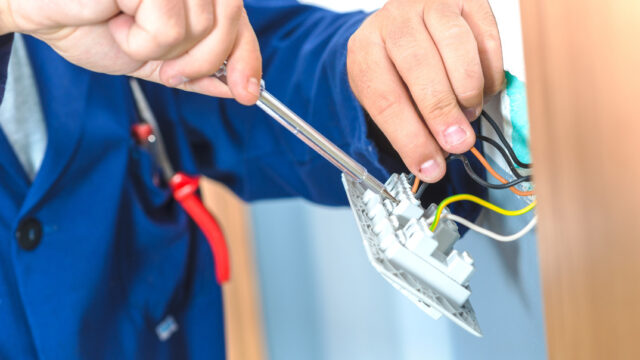 部屋の電気配線作業をする男性。